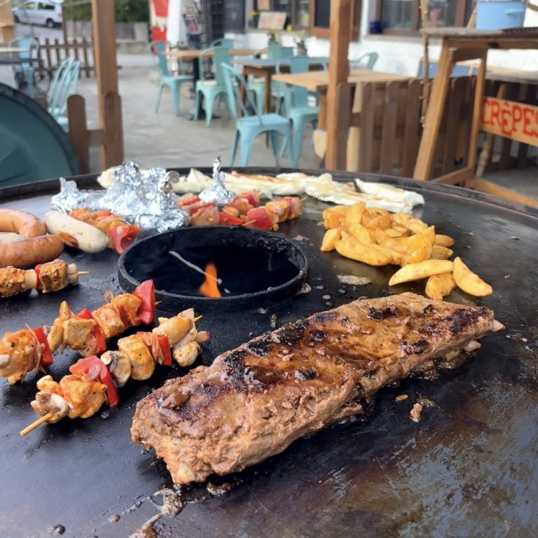 Gesellige Gruppe beim BBQ an der Feuerplatte im Garten des Hotels in Flintsbach – ideal für Teamevents und Aktivurlauber